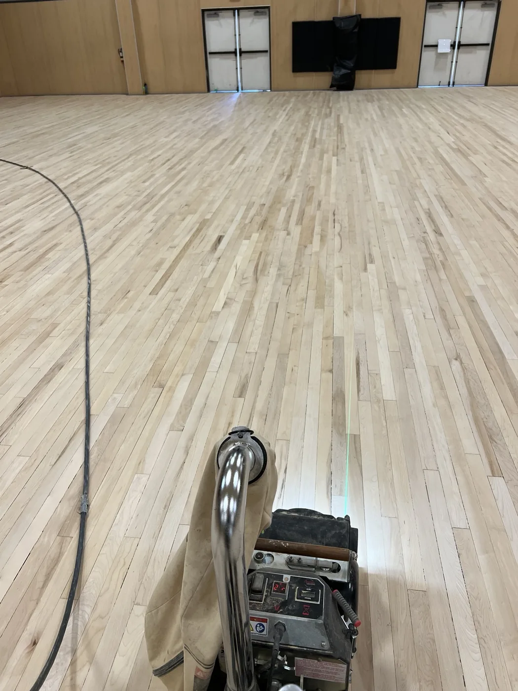 Professional sanding machine on a large hardwood gym floor